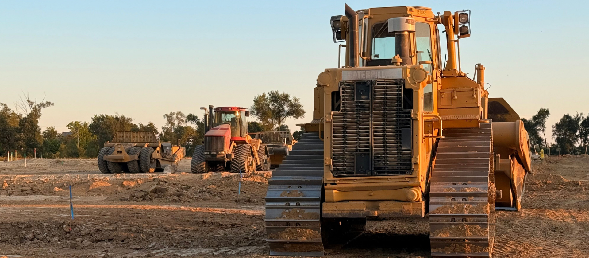 Large yellow bulldozer on a construction site with other equipment in the background.